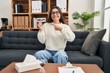 Young hispanic woman going to therapy at consultation office asking for help smiling happy pointing with hand and finger