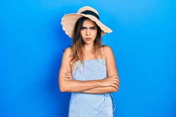 Young hispanic girl wearing summer hat skeptic and nervous, disapproving expression on face with crossed arms. negative person.