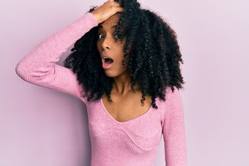 African american woman with afro hair wearing casual pink shirt surprised with hand on head for...
