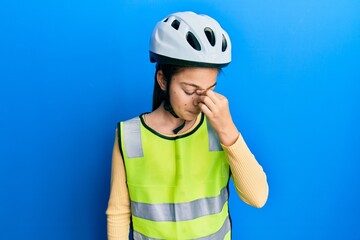 Beautiful brunette little girl wearing bike helmet and reflective vest tired rubbing nose and eyes feeling fatigue and headache. stress and frustration concept.