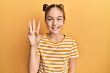 Beautiful brunette little girl wearing casual striped t shirt showing and pointing up with fingers number three while smiling confident and happy.