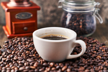  One cup of espresso and coffee beans on wooden surface