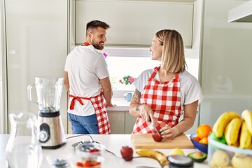 Young couple smiling confident making smoothie cooking at kitchen