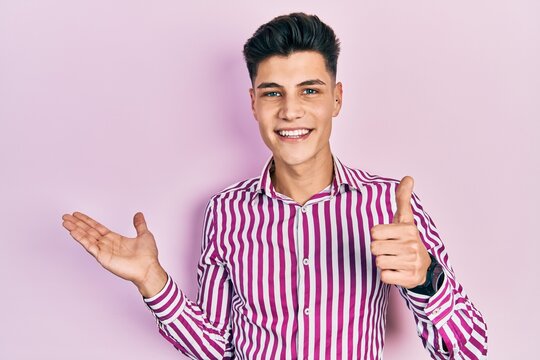 Young hispanic man wearing casual clothes showing palm hand and doing ok gesture with thumbs up, smiling happy and cheerful