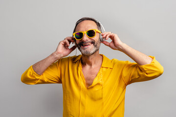 Stylish senior man enjoying music on earphones with sunglasses