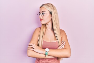 Young blonde girl wearing casual clothes looking to the side with arms crossed convinced and...