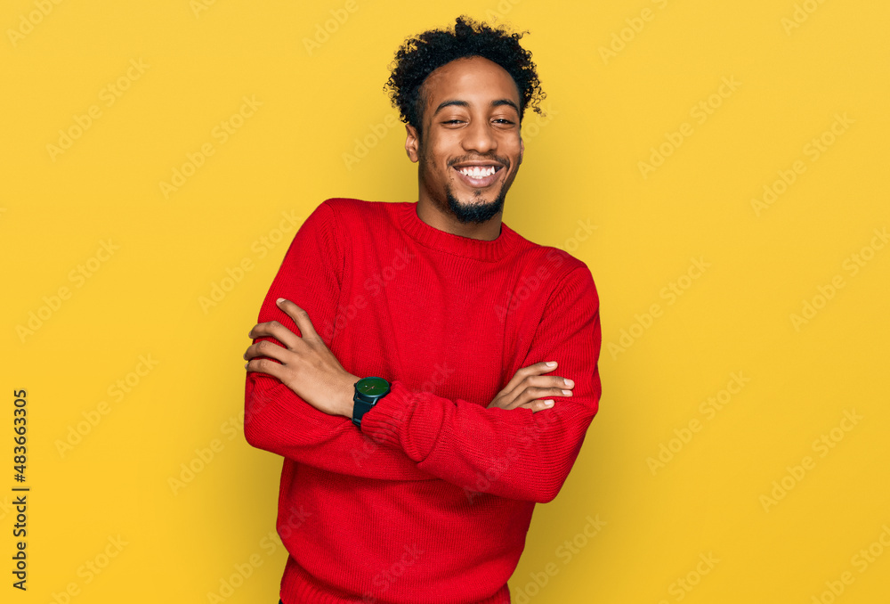 Wall mural Young african american man with beard wearing casual winter sweater happy face smiling with crossed arms looking at the camera. positive person.