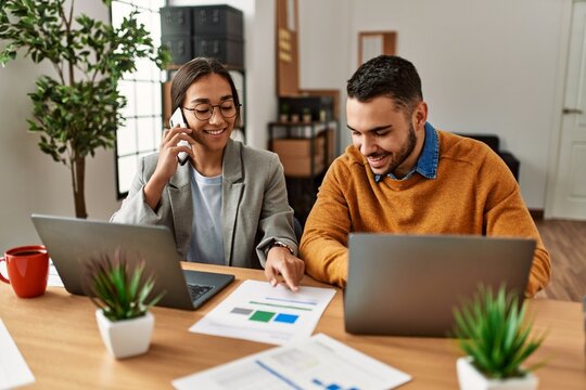 Two business workers talking on the smartphone and using laptop at the office.