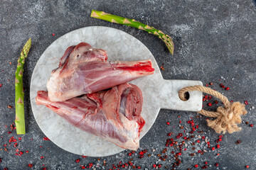 Fresh raw meat of leg young lamb. Raw lamb leg on marble stone background with herbs.