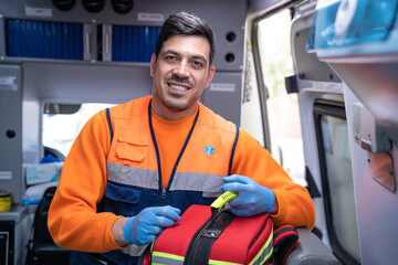 handsome young paramedic smiling inside an ambulance with a medical backpack in his hands. stock photography