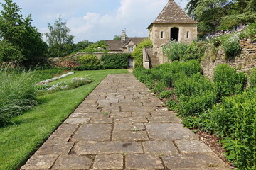 Fototapeta na wymiar scenic view of a stone paved path through a beautiful garden with colourful flowers and green leafy plants
