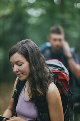 Fototapeta premium Two friends moving through a forest on a hiking vacation, using walking stick branches, guiding their way through the woods