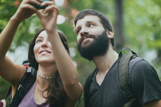 Two friends, hikers, taking a selfie in the forest, updating social media from their adventurous woods exploration