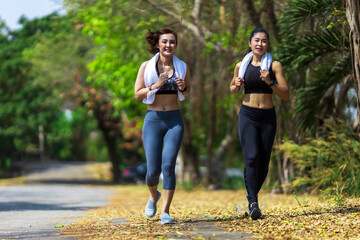 Two Asian woman running in the public park in the morning with warm light for sport, exercise and recreation concep