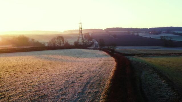 Frosty winter sunrise over farmers fields with a pilon and a road