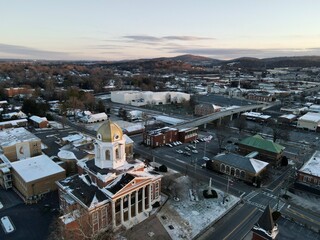 Sunrise light reveals the remaining snow left on the ground and buildings. Small rural town with several neighborhoods around it and historic homes and buildings