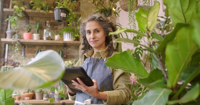 Portrait of Female Small Business Owner looking at Camera Holding Digital Tablet