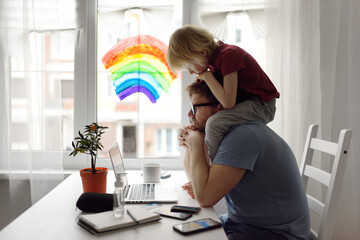 Man is working from home with laptop during quarantine. Home office and parenthood at same time....