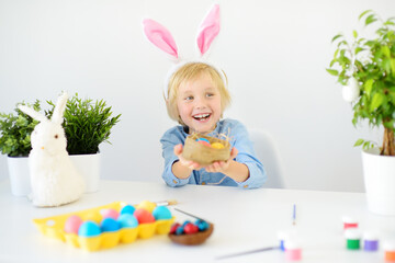 Cute boy paints eggs for Easter holiday. Preparing for celebration is a joy for kids.