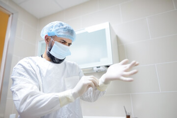Fototapeta na wymiar The surgeon puts on medical protective gloves. Doctor is preparing for surgery in operation room.
