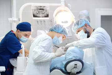 Surgeon and nurse during a dental operation. Anesthetized patient in the operating room....
