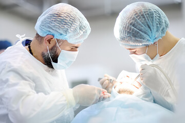Surgeon and nurse during a dental operation. Anesthetized patient in the operating room....