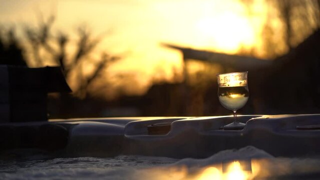 Close up of a glass of sparkling wine in a jacuzzi during sunset.