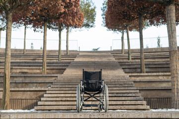 Wheelchair by the stairs without people outdoors. 