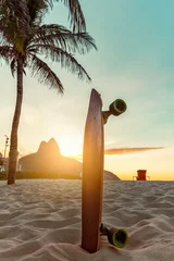 Photo sur Plexiglas Copacabana, Rio de Janeiro, Brésil Skateboard and a Palm Tree on Ipanema Beach, Rio De Janeiro. Sunset light behind famous mountain