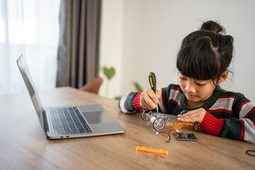 Asian girls enjoy learning online tutor training course at desk table enjoy making and fixing electrical robot car