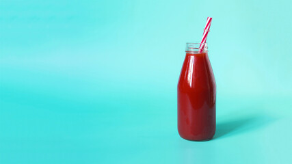 Banner tomato juice in a transparent bottle with a red plastic tube in the sunlight of kopi space.