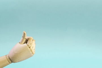 A wooden hand with a raised thumb on a blue background is a place for text. There's nothing wrong...