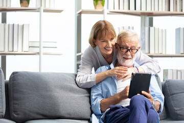 senior couple, elderly man and woman using tablet on sofa