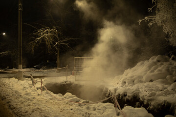 Sewer is excavated at night. Steam from pipe break over pit.