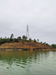 An extra high voltage air duct tower that sits on a small island in green water