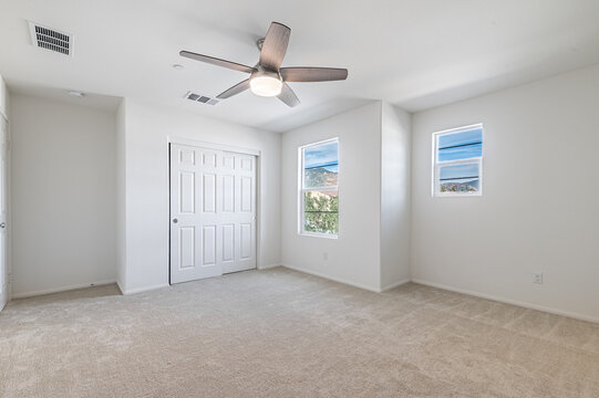An empty new bedroom with bright windows in an upscale modern neighborhood.