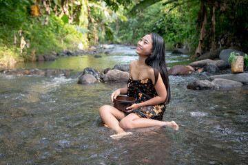 Fototapeta premium Beautiful young Asian girl rests and bathes in the river