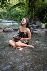 Fototapeta premium Beautiful young Asian girl rests and bathes in the river