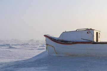 Fishing boat resting in deep snow on the frozen coast near Iqaluit, Nunavut © Jef