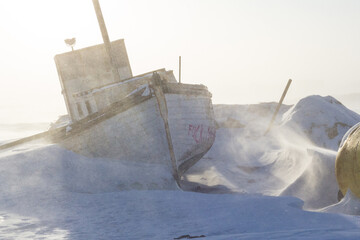 Snow-covered fishing boat in blowing snow near Iqaluit, Nunavut © Jef