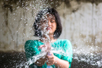 Defocus image of a  little girl playing water splashing with a hose.