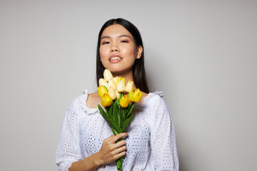 Portrait Asian beautiful young woman romance bouquet of flowers near the face light background unaltered