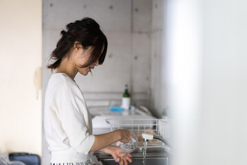 家で洗い物をする若い女性