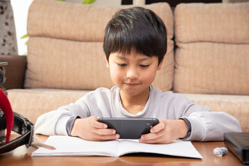 Naklejka premium 宿題をやらないでスマホを見る小学生の男の子