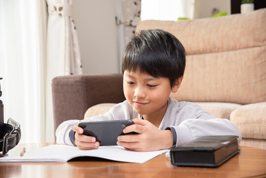 宿題をやらないでスマホを見る小学生の男の子