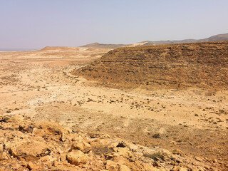 Sandy valley in a rocky terrain. Bright desert view, low volcanic hills, clear blue sky in Cape Verde. Selective focus on the details, blurred background.