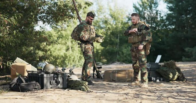Two soldiers prepare for field exercises, responsible work, territorial defense, military on mission, moro uniforms, heavy backpacks, ammo and weapon belts, base in the bushe