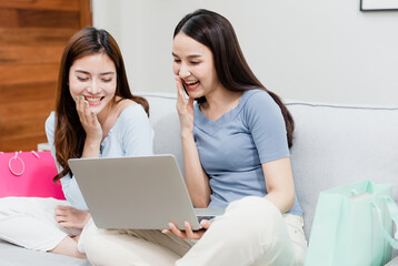 Two Asian beauty people are using a credit card to make purchases using a laptop via the internet. With a happy smiling face, being a new normal online business In the shopping experience from home