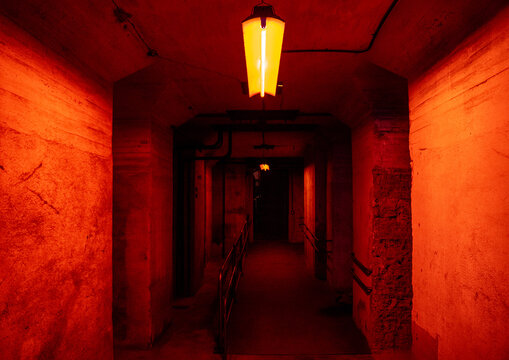 Pasillo claustrof&oacute;bico con iluminaci&oacute;n roja de fluorescentes del interior de un bunker o fabrica abandonada.