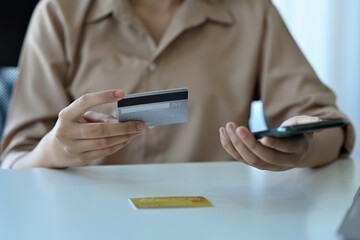 Close up with woman holding credit card and using smartphone, Online shopping, e-commerce, internet banking, spending money concept.